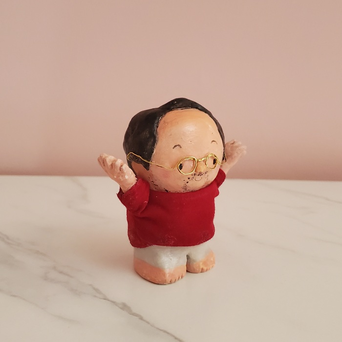 両手を上げて体操するポーズの手作りのおじさん人形。赤い服を着て笑顔で立っている様子。